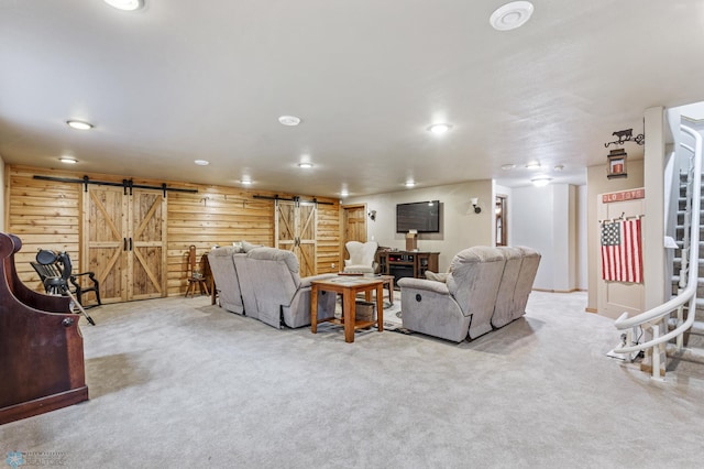 carpeted living room featuring wood walls and a barn door