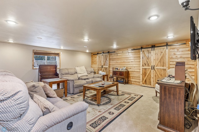 carpeted living room featuring wooden walls and a barn door