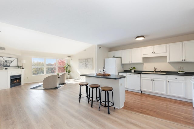 kitchen with white appliances, sink, light hardwood / wood-style floors, white cabinets, and a breakfast bar