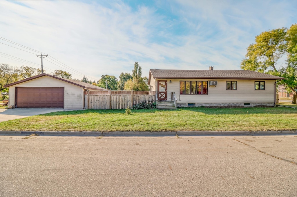 ranch-style house with a garage, a front yard, and an outbuilding