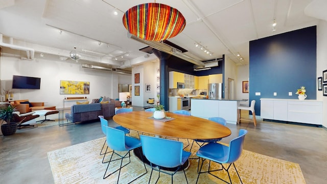 dining space featuring a towering ceiling and concrete floors