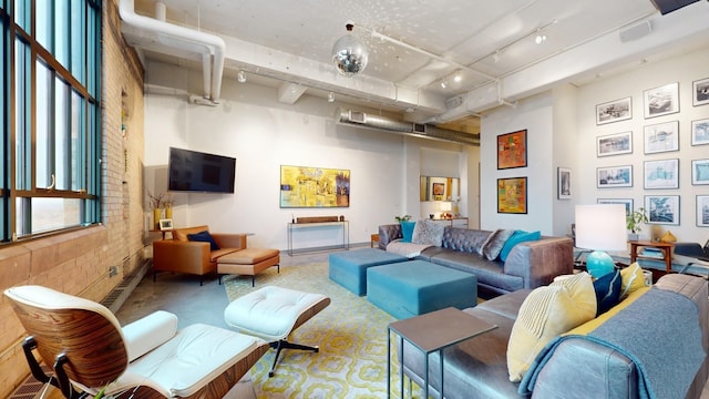 living room with a towering ceiling, rail lighting, and brick wall