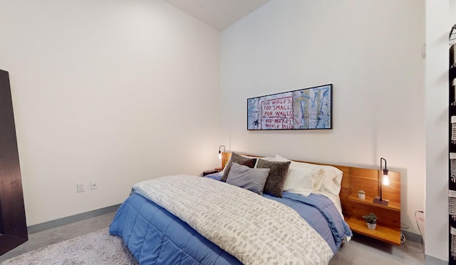 bedroom with finished concrete flooring, lofted ceiling, and baseboards