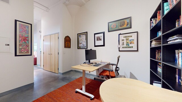 office space with finished concrete flooring, a high ceiling, and visible vents