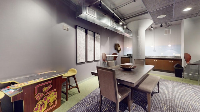 dining room featuring rail lighting, carpet flooring, visible vents, and baseboards