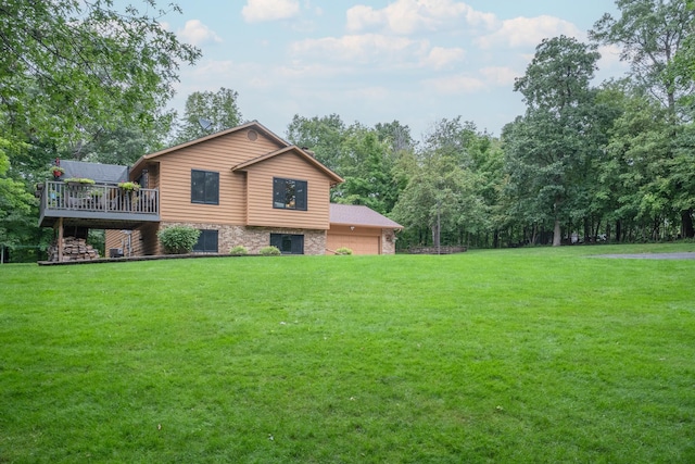 rear view of house with a lawn, a garage, and a wooden deck