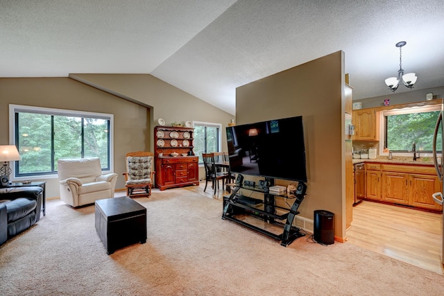 living room with light wood-type flooring, plenty of natural light, lofted ceiling, and a notable chandelier