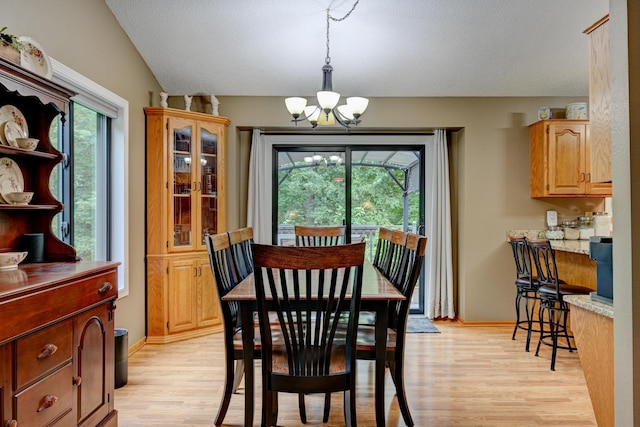 dining space featuring lofted ceiling, light wood-type flooring, and a chandelier