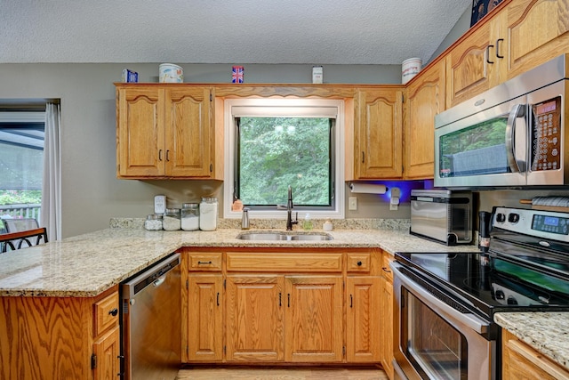 kitchen with sink, light stone countertops, a textured ceiling, kitchen peninsula, and stainless steel appliances