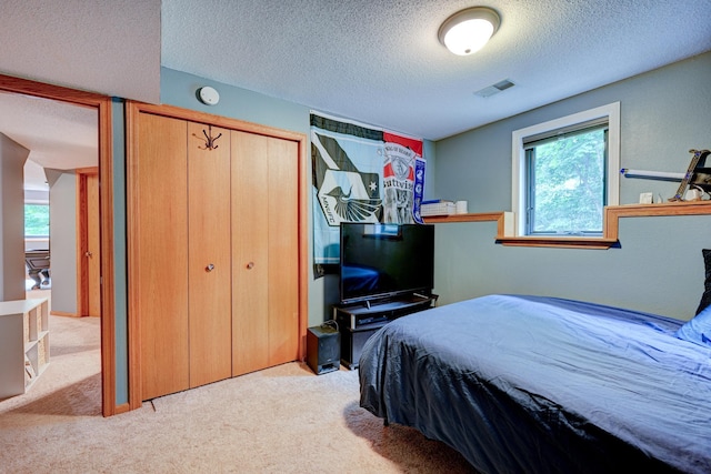 bedroom featuring a textured ceiling, light colored carpet, and a closet