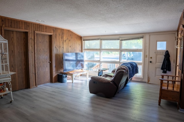 living room with wood walls, hardwood / wood-style floors, and a textured ceiling