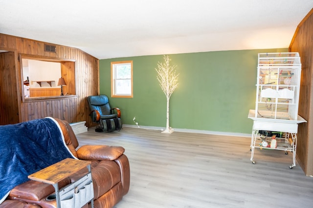 sitting room featuring lofted ceiling, wood walls, and light hardwood / wood-style floors