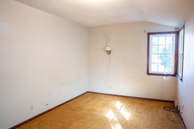 carpeted empty room featuring a textured ceiling and vaulted ceiling