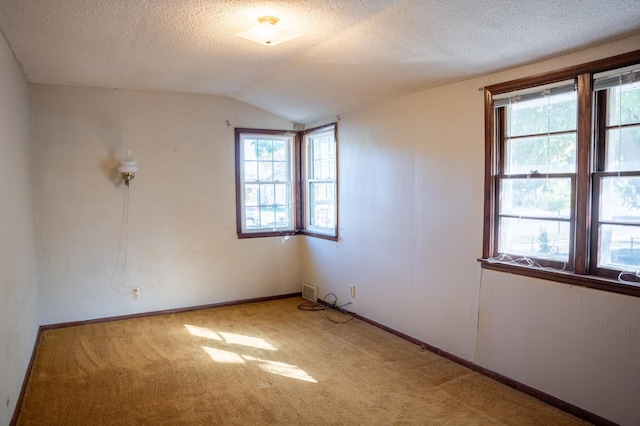 carpeted spare room featuring a textured ceiling and lofted ceiling