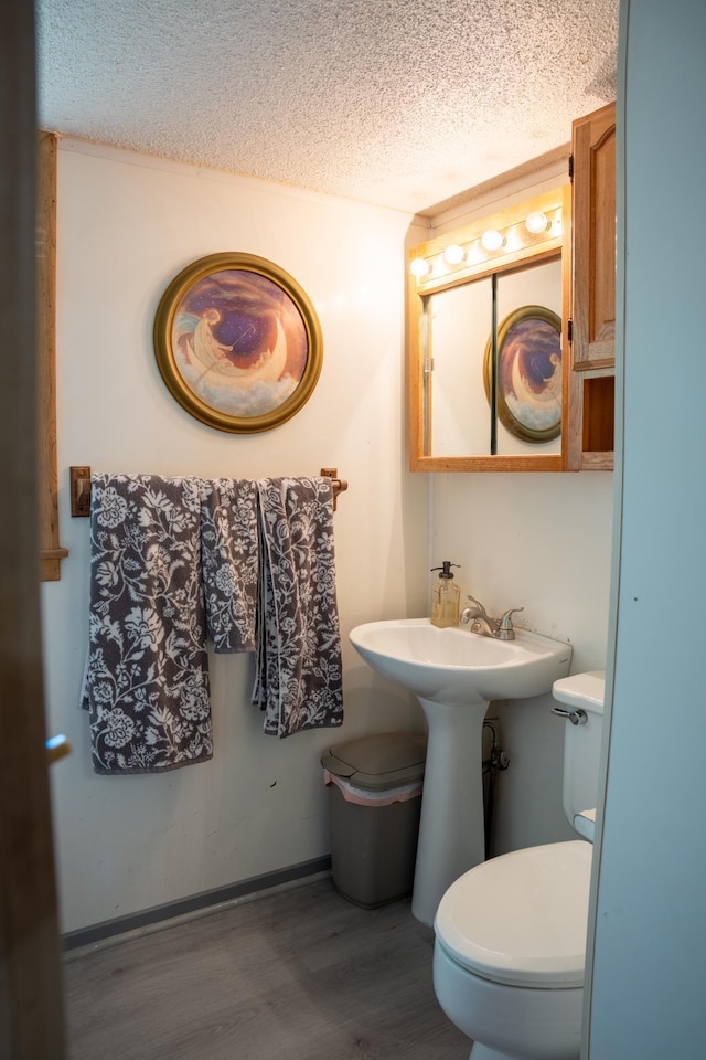 bathroom featuring sink, toilet, hardwood / wood-style floors, and a textured ceiling