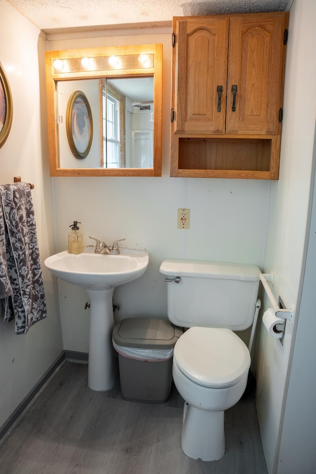 bathroom featuring toilet, sink, hardwood / wood-style floors, and a textured ceiling