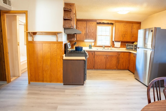 kitchen featuring sink, appliances with stainless steel finishes, light hardwood / wood-style floors, and a textured ceiling