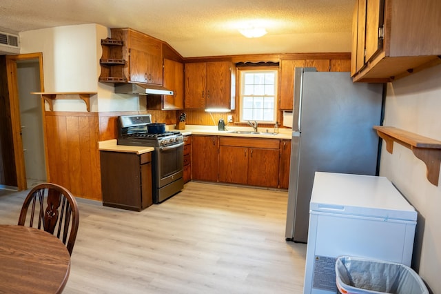 kitchen featuring a textured ceiling, stainless steel appliances, sink, and light hardwood / wood-style flooring