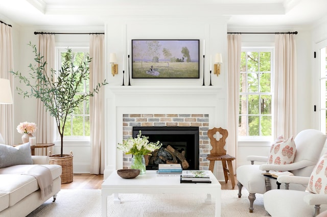 sitting room with a brick fireplace, light hardwood / wood-style flooring, and plenty of natural light