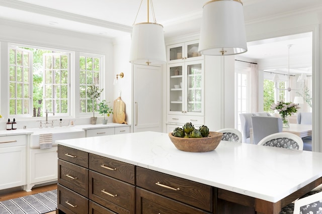 kitchen featuring decorative light fixtures, a kitchen island, white cabinetry, and crown molding