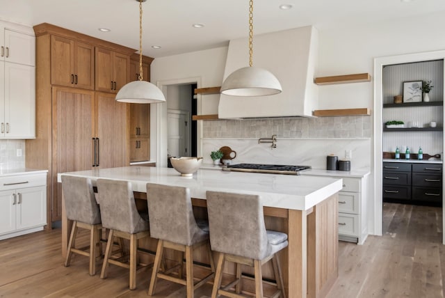 kitchen with a kitchen island, white cabinetry, stainless steel gas cooktop, and tasteful backsplash