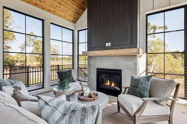 sunroom with a fireplace, a healthy amount of sunlight, lofted ceiling, and wood ceiling