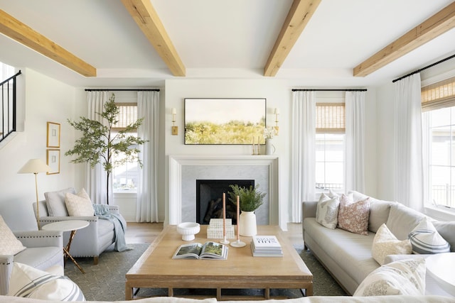 living room with hardwood / wood-style flooring, a premium fireplace, and beamed ceiling