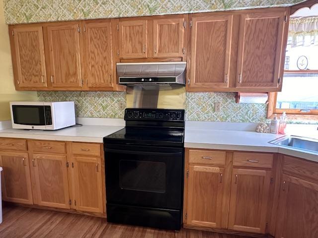 kitchen with black range with electric cooktop, sink, tasteful backsplash, and light hardwood / wood-style flooring