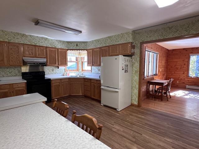 kitchen with black / electric stove, freestanding refrigerator, dark wood-style floors, and extractor fan