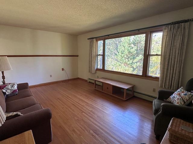 living area with baseboards, wood finished floors, and a textured ceiling