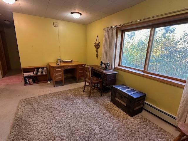 carpeted office space with a baseboard heating unit