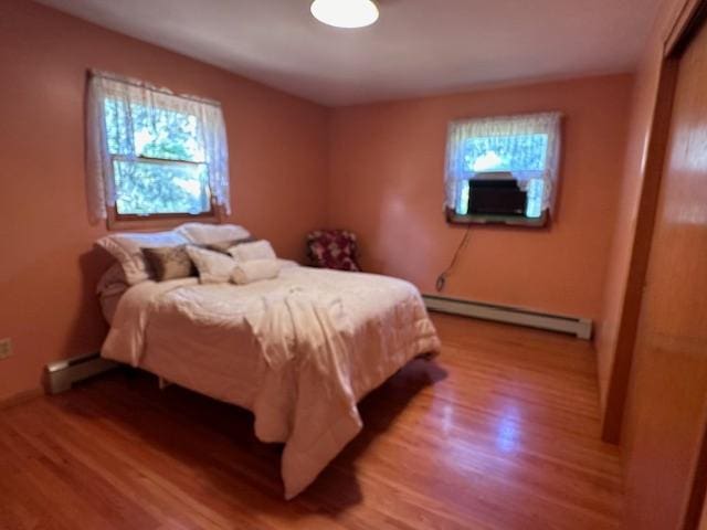 bedroom with baseboard heating, a baseboard radiator, and light wood-style flooring