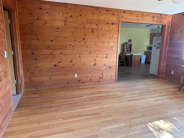 empty room with wooden walls and light wood-style flooring