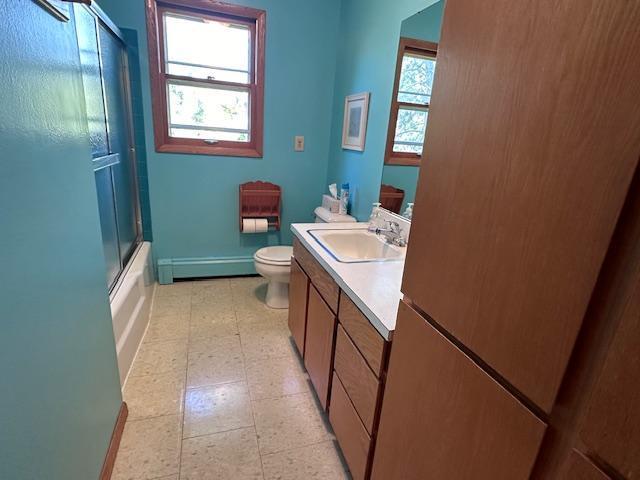 full bathroom with vanity, baseboard heating, toilet, tile patterned floors, and baseboards