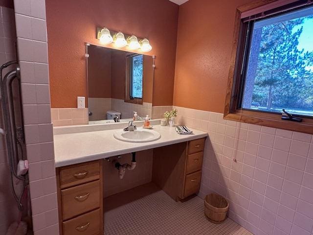 bathroom featuring tile patterned floors, tile walls, vanity, and a wainscoted wall