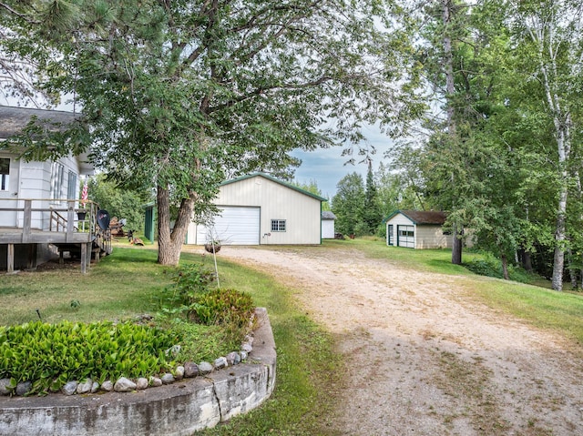 view of front of property featuring a detached garage, a front lawn, an outdoor structure, and driveway