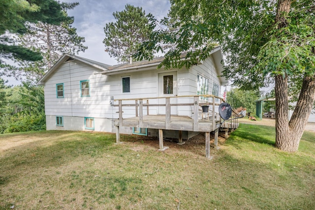 back of property with a deck and a lawn