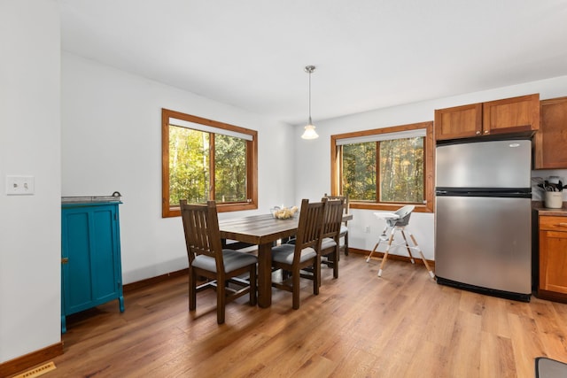 dining room with a barn door, light hardwood / wood-style floors, and a healthy amount of sunlight