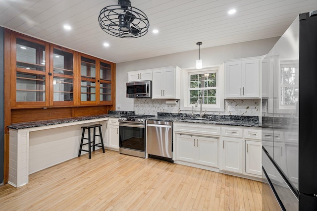 kitchen with pendant lighting, appliances with stainless steel finishes, light hardwood / wood-style flooring, and white cabinetry