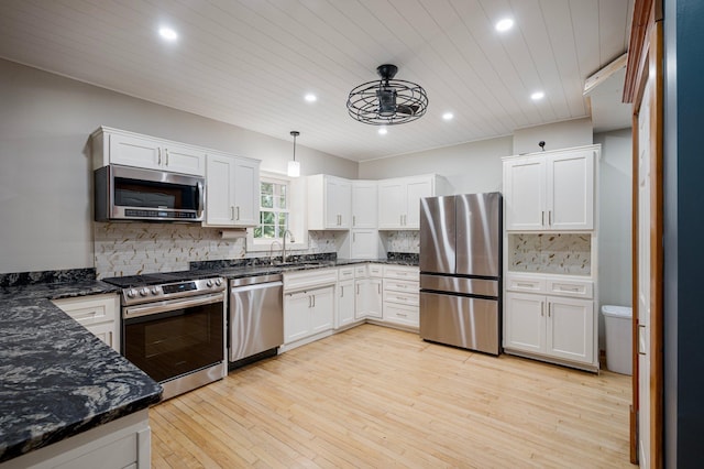 kitchen featuring pendant lighting, white cabinets, stainless steel appliances, light wood-type flooring, and decorative backsplash