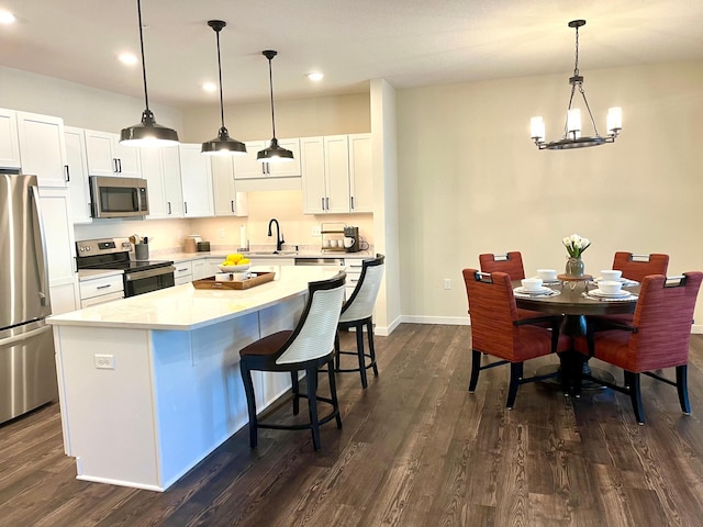 kitchen with pendant lighting, appliances with stainless steel finishes, dark hardwood / wood-style flooring, and a center island