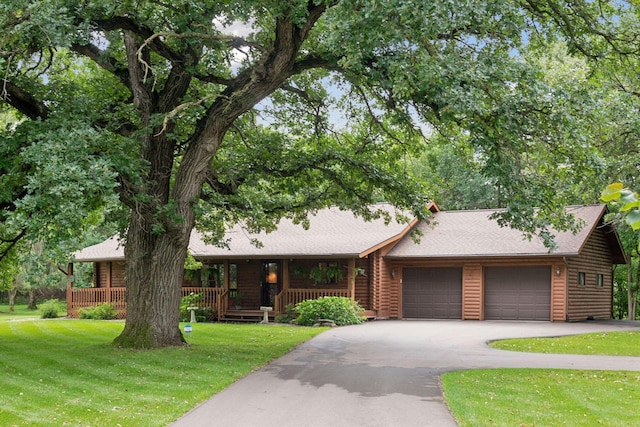 single story home featuring a garage, a porch, and a front yard