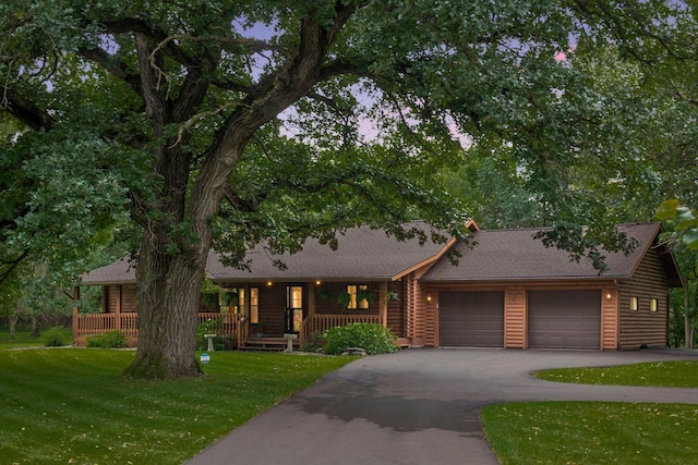 view of front of home with covered porch, a front yard, and a garage