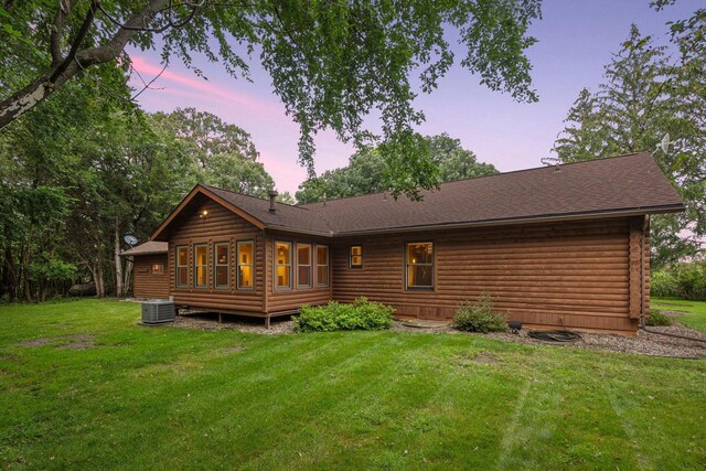 back house at dusk featuring a yard and central air condition unit