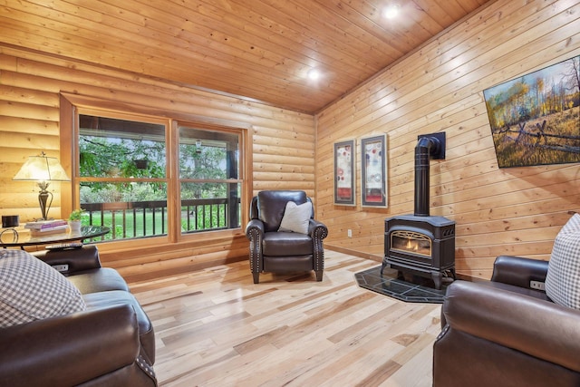 living room with log walls, wooden ceiling, light hardwood / wood-style flooring, and a wood stove