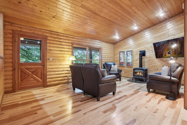 living room with a wood stove, a wealth of natural light, wooden ceiling, and light hardwood / wood-style flooring