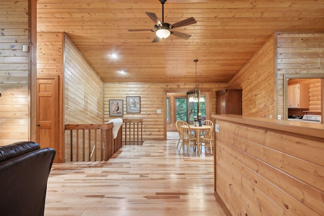 interior space featuring ceiling fan with notable chandelier, light wood-type flooring, wood walls, and wooden ceiling