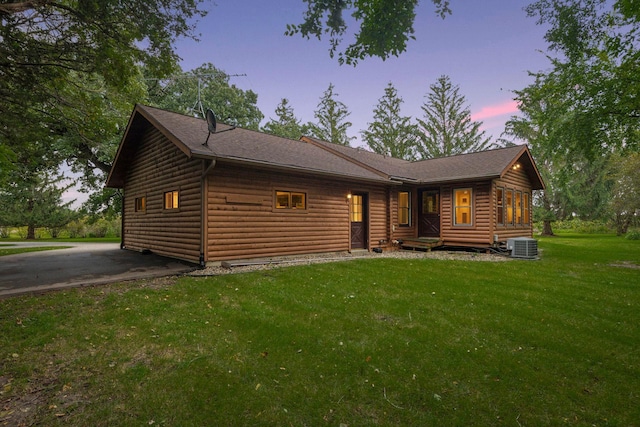 view of front of home featuring cooling unit and a yard