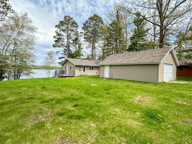 view of yard featuring a garage, a deck with water view, and an outdoor structure