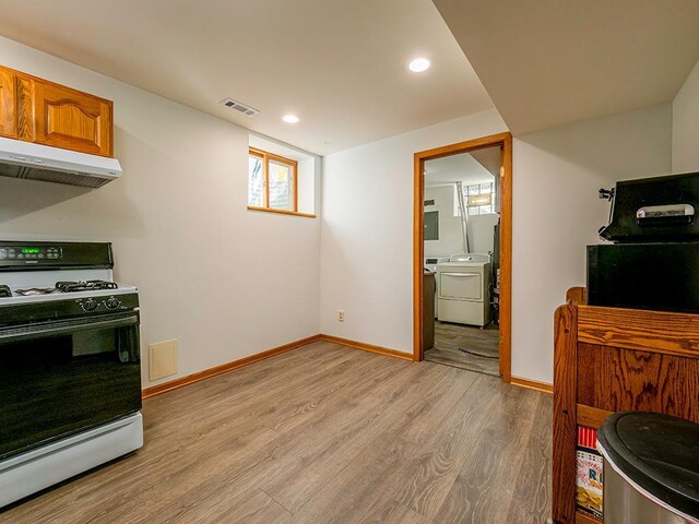 kitchen with white gas range oven, separate washer and dryer, and light hardwood / wood-style floors